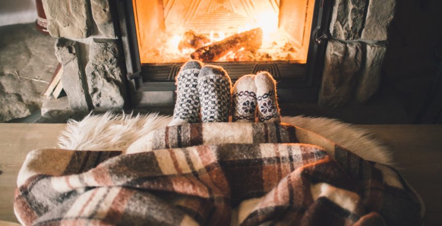 Feet in woollen socks by the Christmas fireplace.